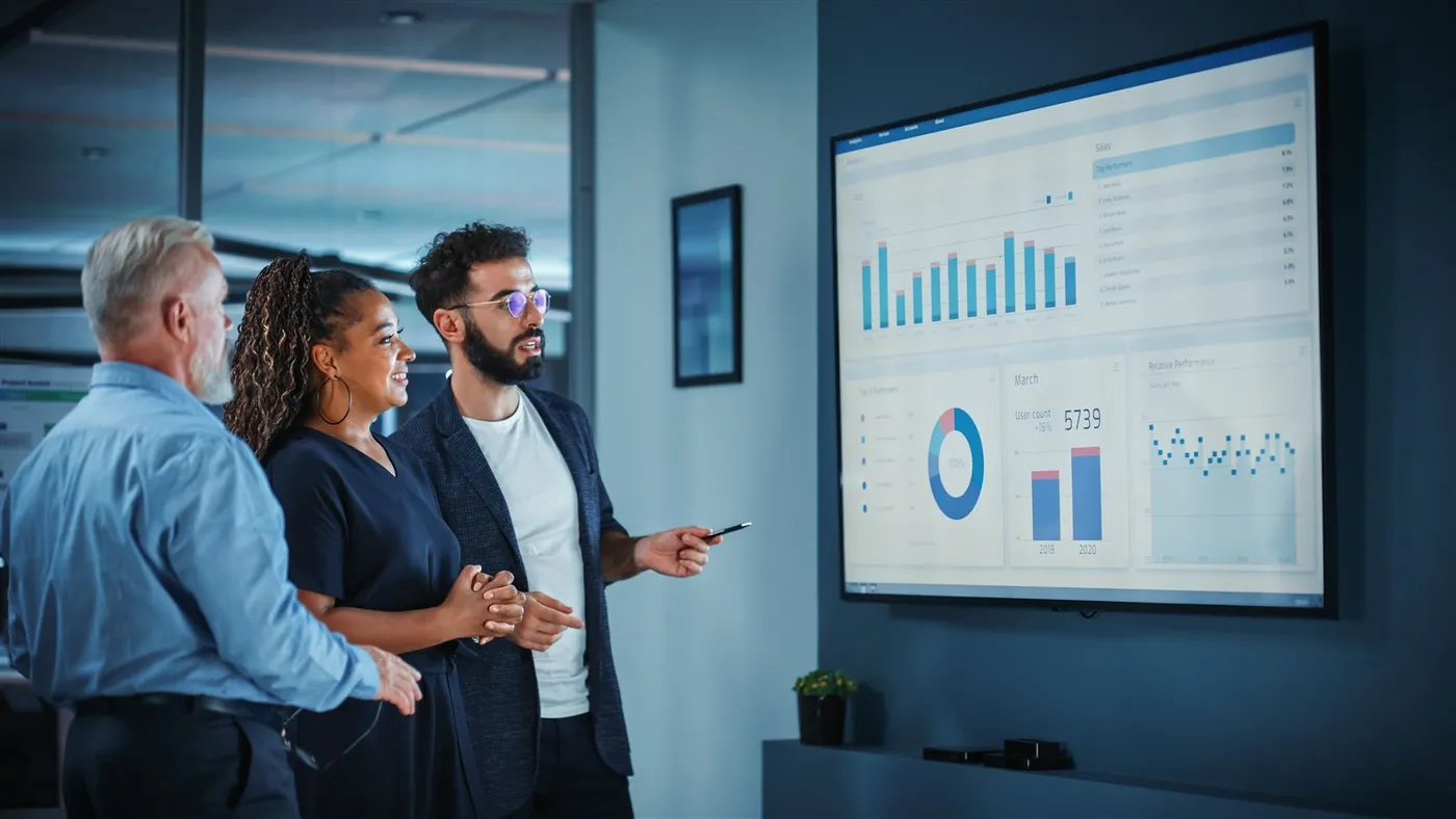 An agency team reviewing performance dashboards on a wall screen