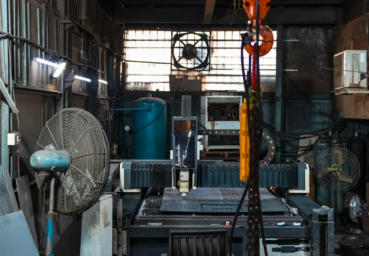 A fabrication workshop floor with a large CNC cutting machine