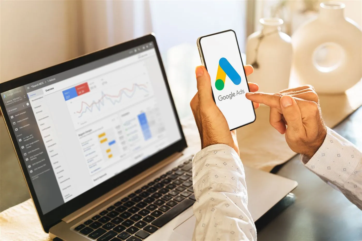 A Google Ads account dashboard open on a laptop and phone
