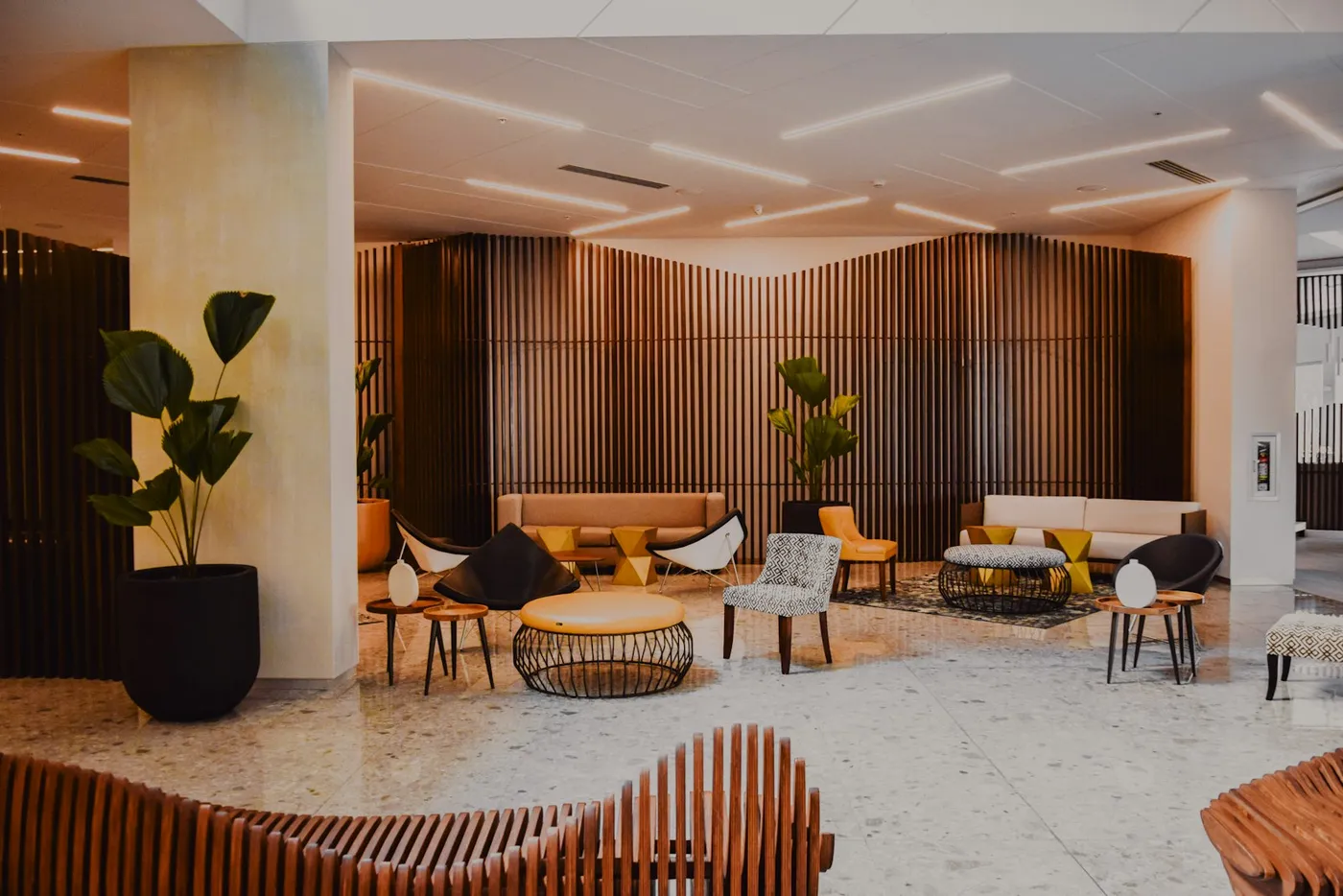A modern hotel lobby with designer seating and timber-slat walls