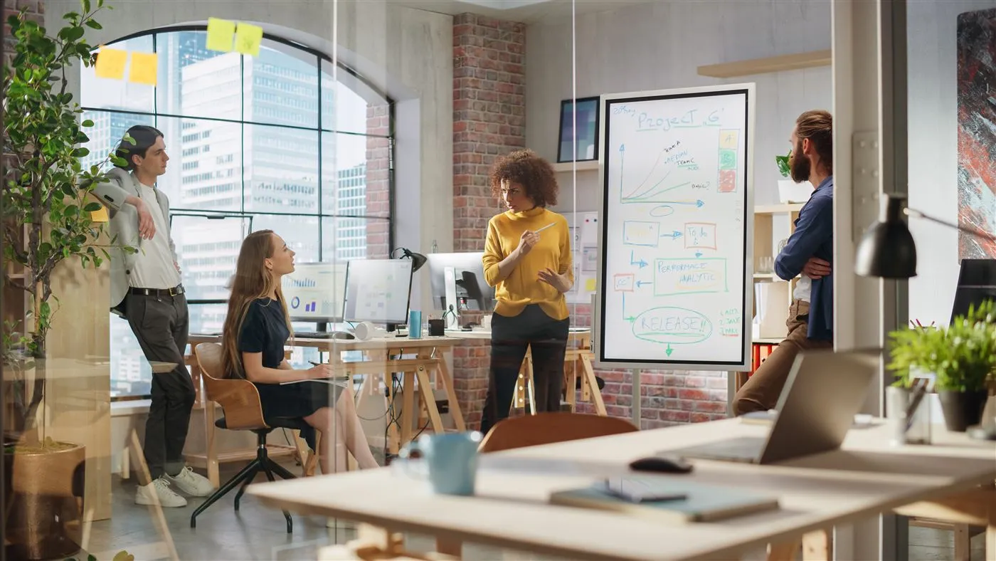 A team debating a project plan at a whiteboard in a bright office