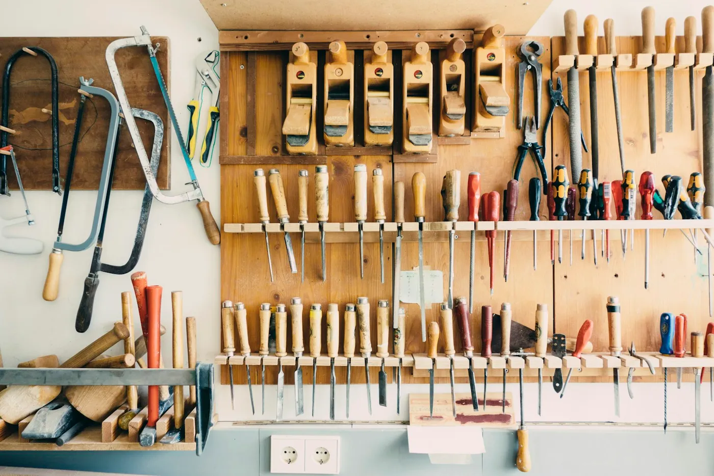 Hand tools hanging in a rack on a workshop wall