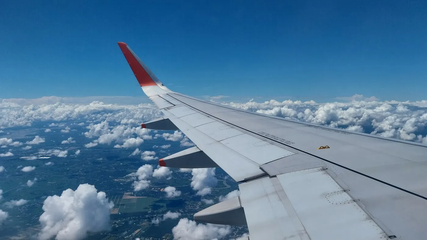 An aeroplane wing above clouds seen from a passenger window