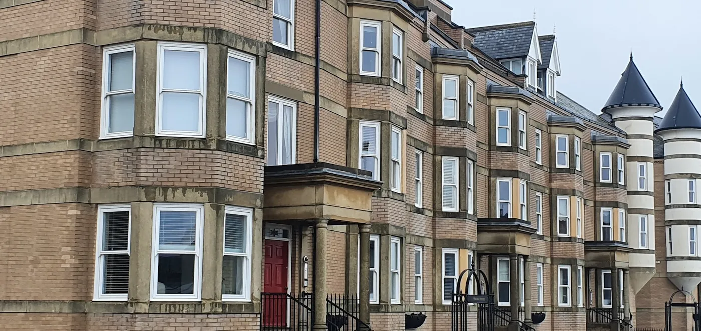 A row of British brick terraced houses with bay windows